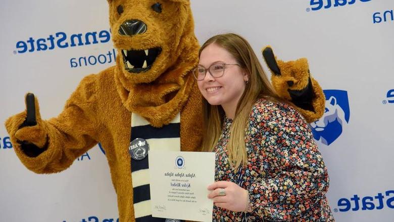 毕业于心理学专业的凯莉·瑞舍尔在毕业典礼后与她的证书和尼塔尼狮子合影留念.